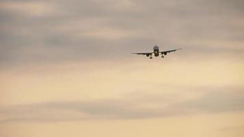 Airliner in the evening sky on final approach before landing. View from the runway's edge video