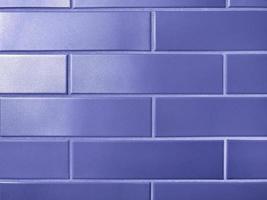 New wall tiled bricks with a silvery gray shade repainted in trendy very peri color of the year 2022. Modern facade made of violet ceramic tiles. Horizontal image background, straight lines.