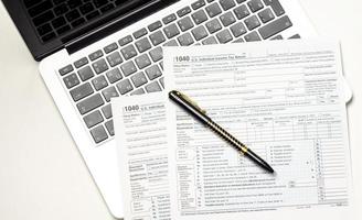 vista de formulario de impuestos con bolígrafo, calculadora y computadora portátil foto