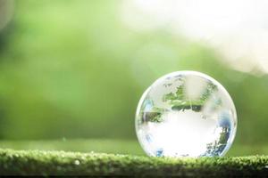 globo planeta cristal en bosque verde con luces de naturaleza bokeh. día Mundial del Medio Ambiente. concepto para la conservación del medio ambiente, proteger la ecología de la tierra y la vida ecológica con espacio de copia foto