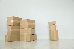 Stack of cardboard boxes for moving, Empty room with a white wall and cardboard boxes with unbranded barcode on the floor. Delivery of goods, shopping. Cardboard boxes on gray wall background. photo