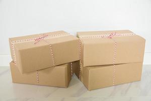 pila de cajas de cartón para mudanzas, habitación vacía con una pared blanca y cajas de cartón con código de barras sin marca en el suelo. entrega de mercancías, compras. cajas de cartón sobre fondo de pared gris. foto