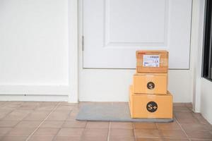 Cardboard parcel box near door on floor. Online shopping, boxes delivered to your front door. Easy to steal when nobody is home. Parcel in cardboard box on doorstep. Delivery service photo