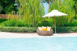 outdoor patio chair with pillow and umbrella around swimming pool photo