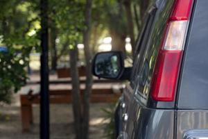 Black car tail lights with the car parked facing the shaded area of the trees in the park. Blurred of trees in park area. photo