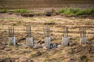 filas de cimientos de pilotes de hormigón perforando el suelo en el sitio de construcción cerca del río. La base de pilotes es una base de uso común para soportar cargas verticales pesadas. foto