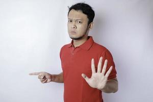 Attractive Asian man with hand gesture pose rejection or prohibition while pointing to copy space by his side photo