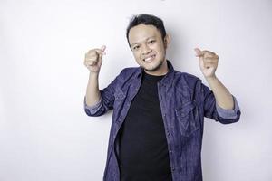 An attractive young Asian man wearing a navy blue shirt feels happy and a romantic shapes heart gesture expresses tender feelings photo