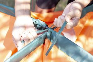 Hand of Tourists are use a rope to tie the pole on top of the tent for camping tonight. photo