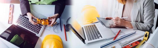 Two colleagues discussing data working and tablet, laptop with on on architectural project at construction site at desk in office photo
