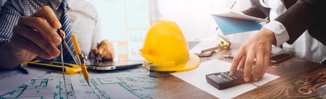 Two colleagues discussing data working and tablet, laptop with on on architectural project at construction site at desk in office photo
