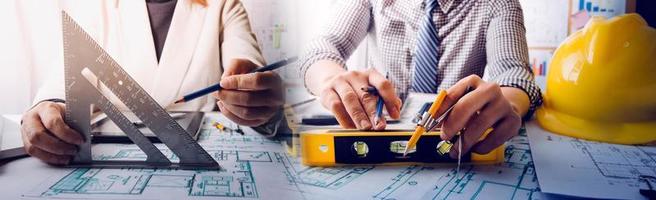 Two colleagues discussing data working and tablet, laptop with on on architectural project at construction site at desk in office photo