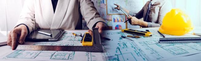 Two colleagues discussing data working and tablet, laptop with on on architectural project at construction site at desk in office photo