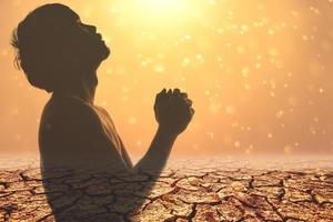 orando por lluvia, pidiendo agua para sobrevivir a la crisis de escasez de agua. concepto de orar a dios. silueta de un hombre rezando. foto