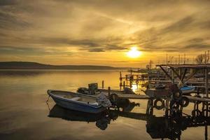 Stunning sunset at the harbor with a wooden pier and wooden boat photo