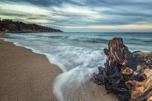 paisaje marino, magnífico paisaje marino de larga exposición con un tronco en la costa del mar negro, bulgaria foto