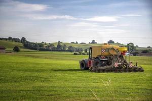 Application of manure on arable farmland with the heavy tractor who works at the field in Germany photo