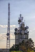 torre de comunicaciones móviles con dispositivos de control y antenas, transmisores, comunicaciones móviles e Internet al atardecer foto