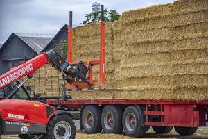 Varna, Bulgaria - September 19, 2016.  Telescopic handler Manitou Maniscopic take bales from a truck. Day view. Work in port. photo