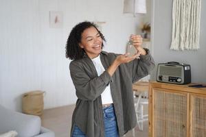 Joyful biracial teen girl tenant homeowner shows home keys to new first house, celebrates relocation photo