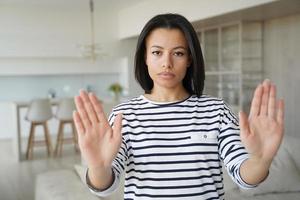 Serious woman showing stop hand gesture protesting against domestic violence, abuse or abortion photo