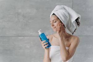 Pretty woman holds shower gel or shampoo mockup bottle, advertising cosmetics for washing, cleansing photo