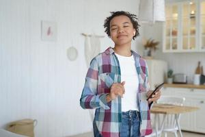 Mixed race young girl listens to music, enjoying sound using musical apps on mobile phone at home photo