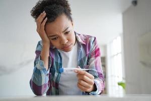 Unhealthy mixed race girl holds thermometer suffers from high body temperature, fever, covid symptom photo