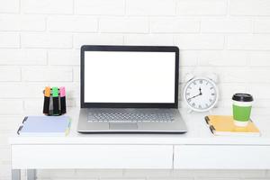 accesorios educativos en la mesa cerca de la pared de ladrillo. computadora vacía y pantalla móvil con lugar para texto. foto