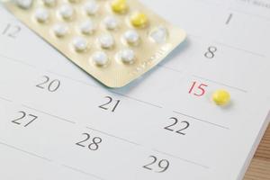 píldoras anticonceptivas en la fecha de fondo del calendario. concepto de salud y medicina foto