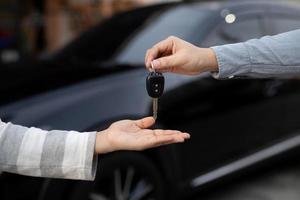 la llave del auto, el hombre que entrega le da la llave del auto al otro hombre en el auto como fondo de casa. deje espacio para escribir una descripción del texto del mensaje. foto