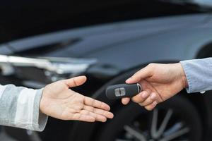 Car key, man handing over gives the car key to the other male on car an home background. Leave space to write a description of the message text. photo