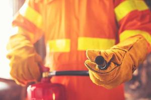 mano de bombero sosteniendo extintor de incendios. disponible en emergencias conflagración daños antecedentes. concepto de seguridad foto