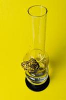 Marijuana bud and bong on yellow background, close up photo