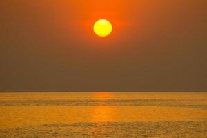 el sol cayó en la tarde. color dorado brillante que refleja el agua del mar foto