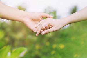 Young couple lover show holding hands make heart shape over in public parks. photo