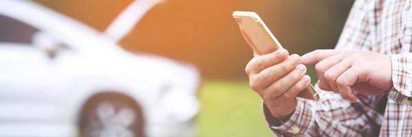 close up businessman hand using a mobile smart phone call a car mechanic ask for help assistance because car broken roadside. people journey friends standing wait beside broken car background. photo