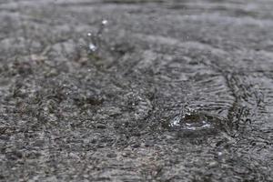 gotas de lluvia en el agua pesada sobre sombra de asfalto de sombra negra y reflejo del cielo oscuro en la ciudad. alto contraste durante el otoño foto