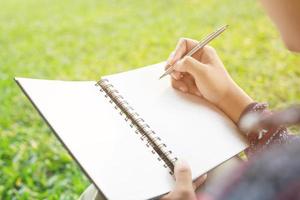 Top view close up hand woman are writing notepad down cost into the book photo