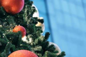 Closeup of red bauble hanging from a decorated christmas tree on blurred of  lights with decorated tree, sparkling and bokeh background. copy space for your text. photo