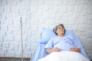 An elderly woman lying on bed in the recovery room. Healthcare and medicine concept. photo