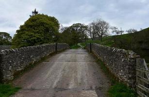 puente de piedra a través de tierras de cultivo rurales en inglaterra foto