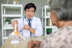 The doctor is explaining to the senior patient the foot pain with model. photo