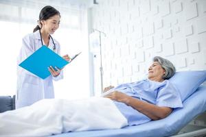 hermoso médico asiático con estetoscopio y carpeta de documentos, examine el síntoma del paciente en la sala de recuperación. concepto de salud y medicina. foto