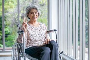 Happy elderly asian woman sitting on wheelchair at home. photo
