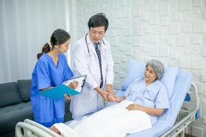 doctor visiting ward have woman patient and check her with stethoscope on bed. Woman patient lying on hospital bed while doctor giving her checkup. photo