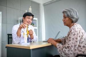 The doctor is explaining to the senior patient the foot pain with model. photo