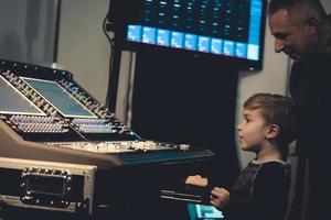 Music producer and little boy edit sound on audio mixer. photo