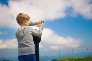 Little boy looking through telescope while exploring the nature. photo