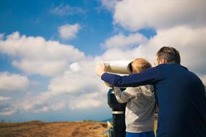 Father and son exploring the sky through coin operated binoculars. photo